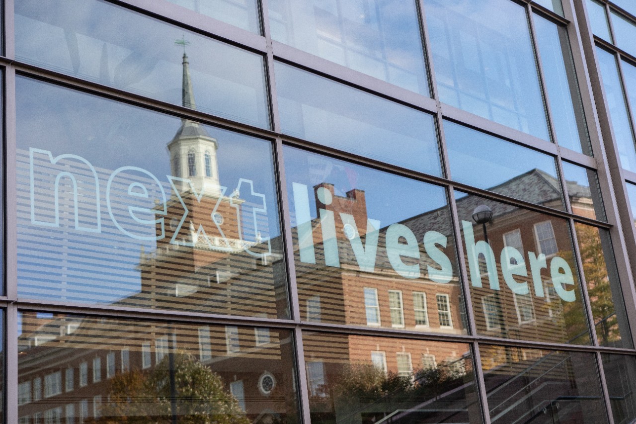 UC campus window with Next Lives Here logo